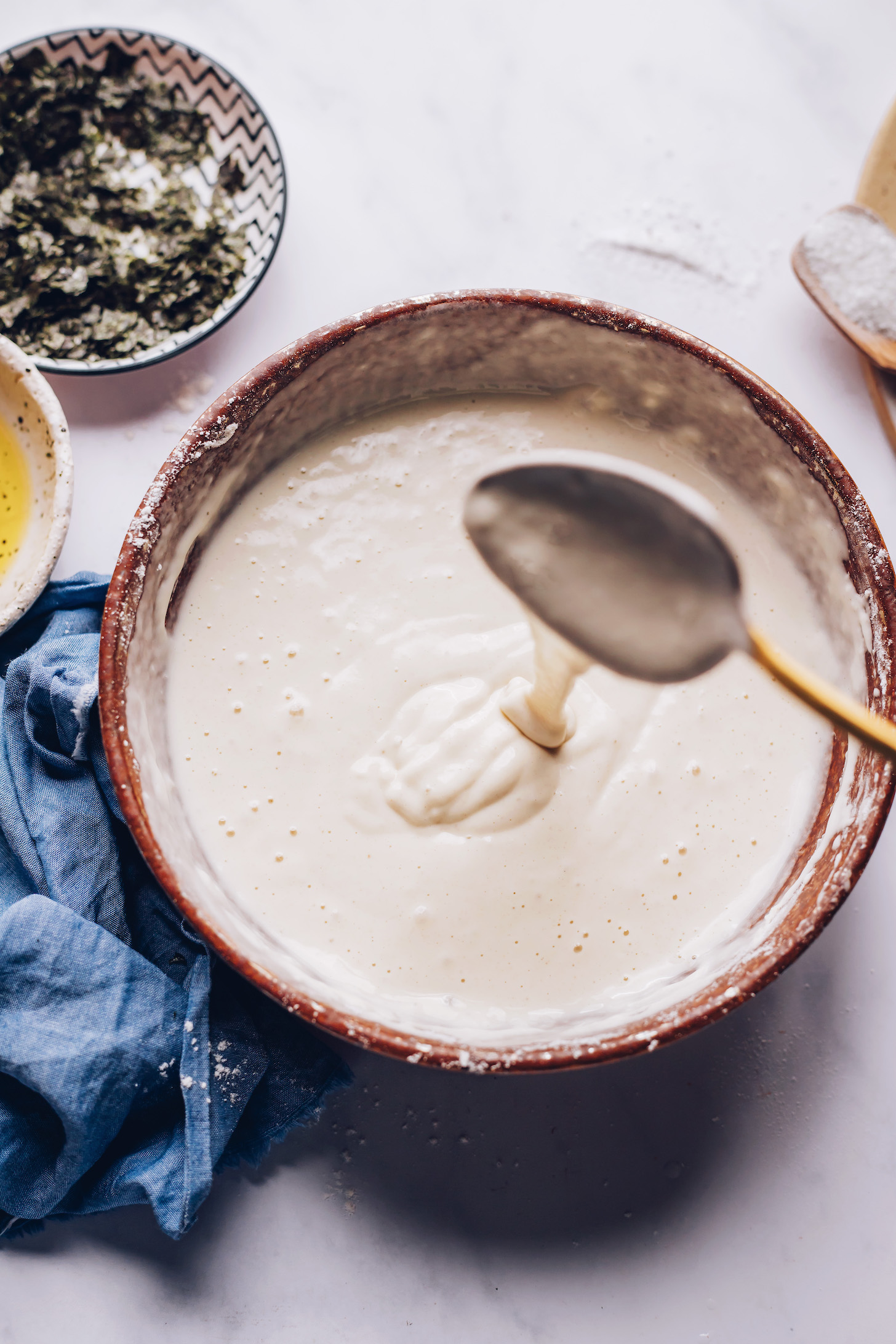 Batter falling off a metal spoon into a bowl