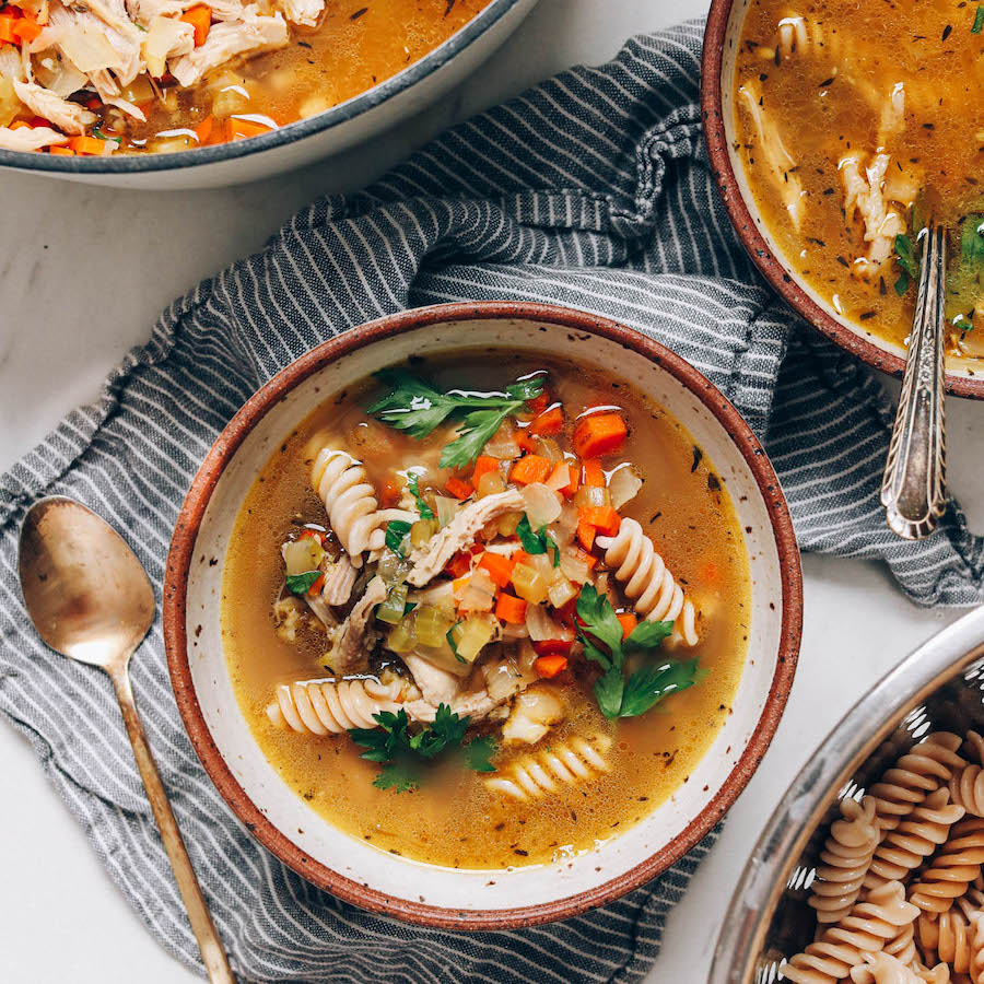 Bowls of chicken noodle soup topped with fresh parsley