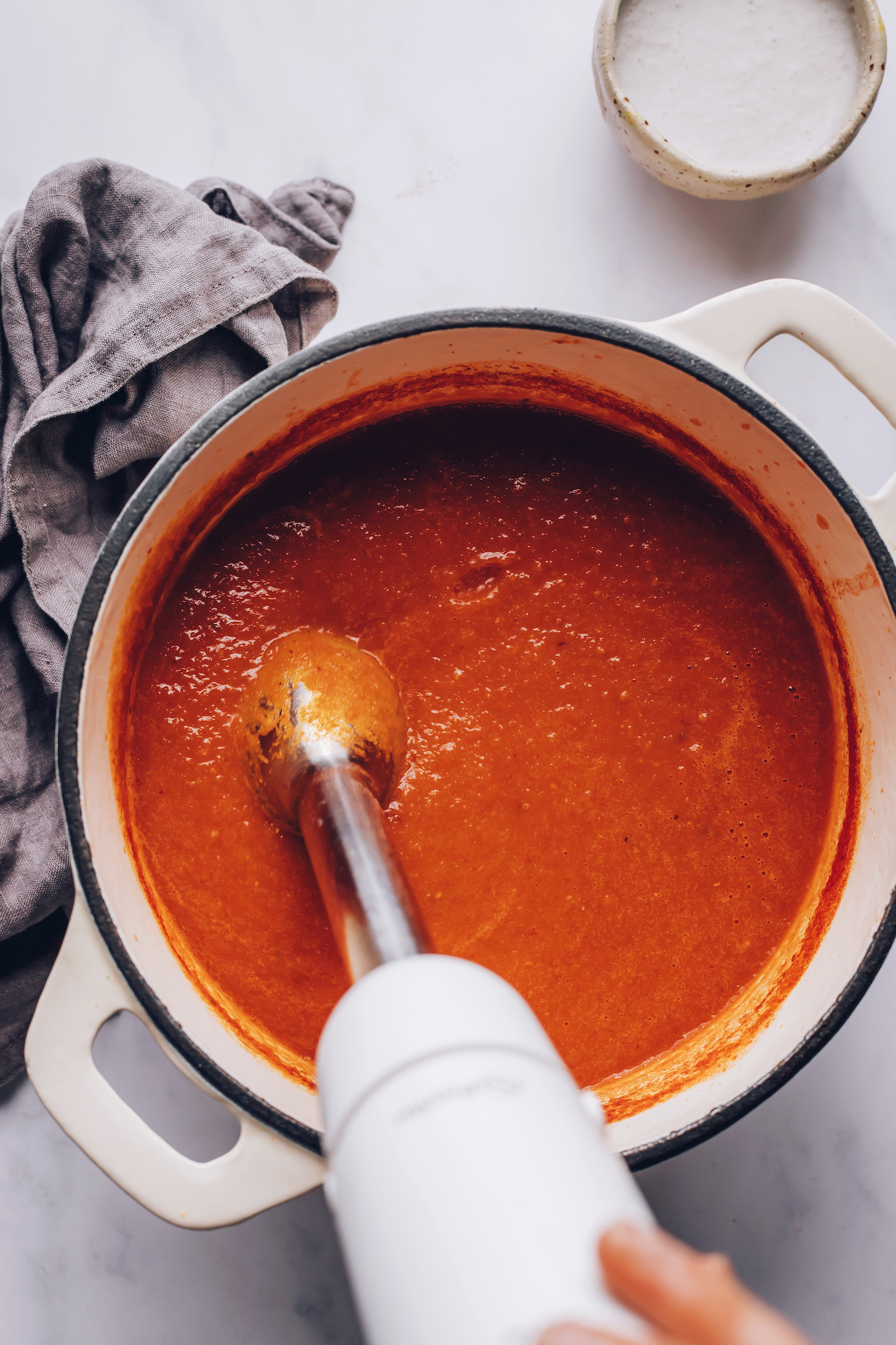 Using an immersion blender to blend spicy tomato soup