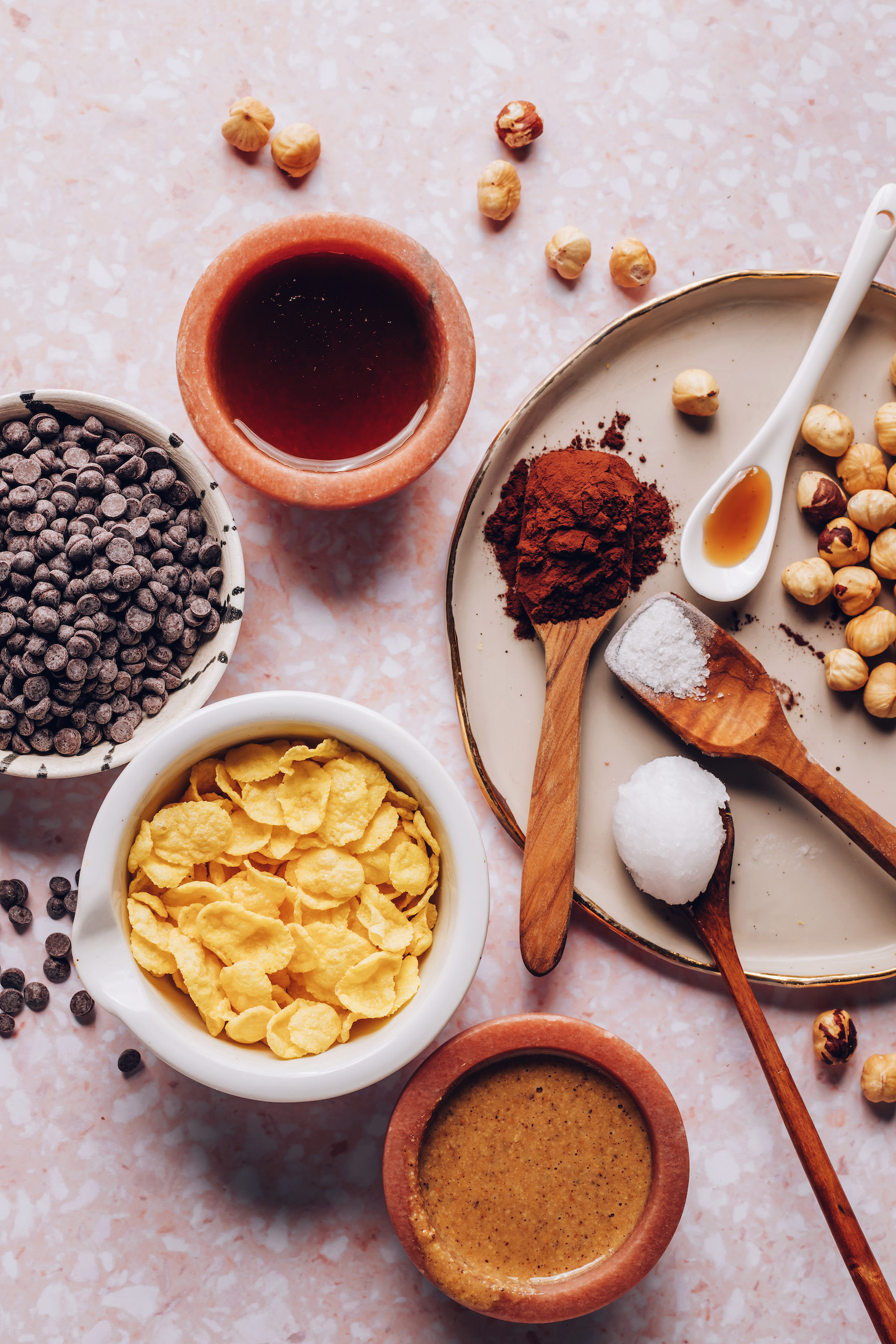 Mini chocolate chips, cornflakes, maple syrup, hazelnut butter, cocoa powder, coconut oil, salt, vanilla, and hazelnuts