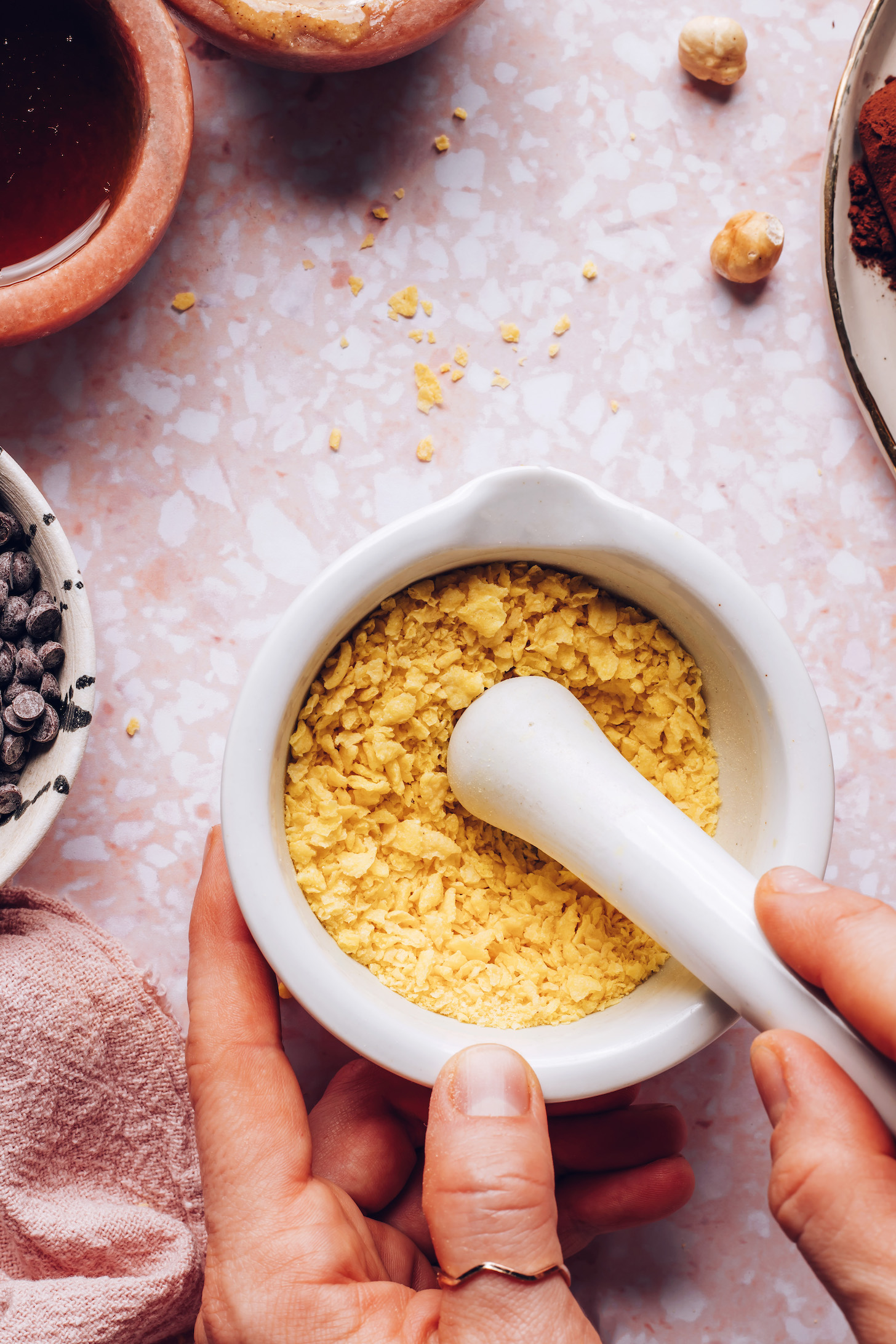 Crushing cornflakes in a mortar and pestle