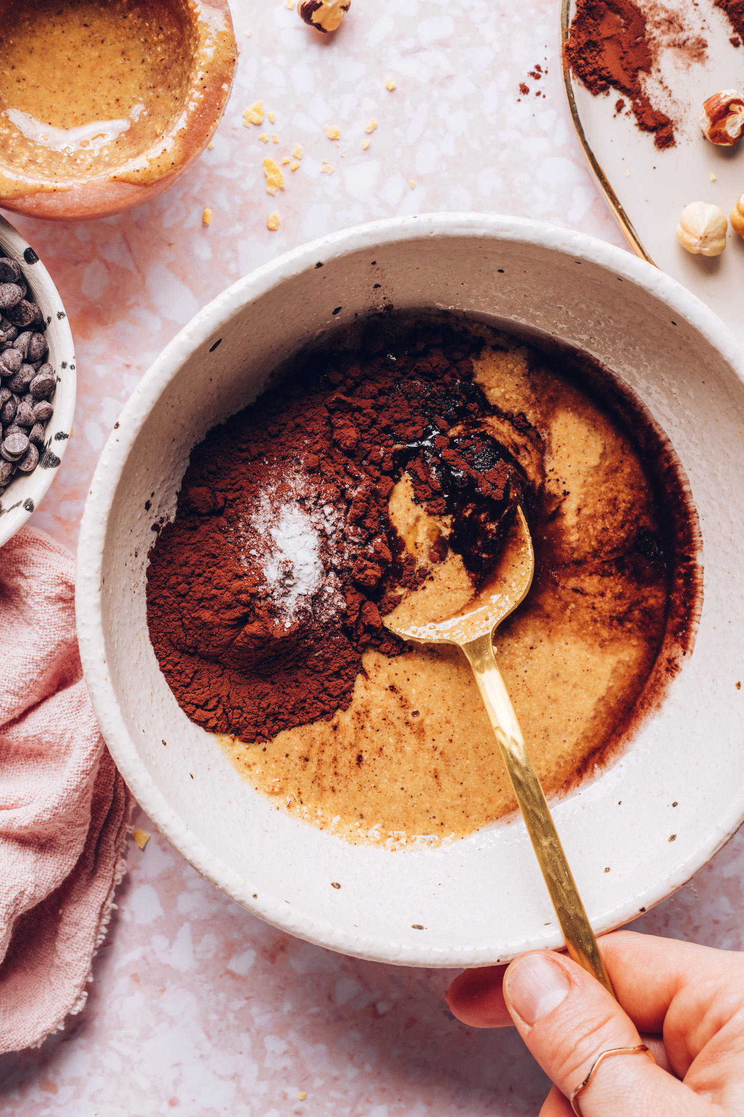 Stirring cocoa powder, hazelnut butter, maple syrup, coconut oil, vanilla, and salt in a bowl