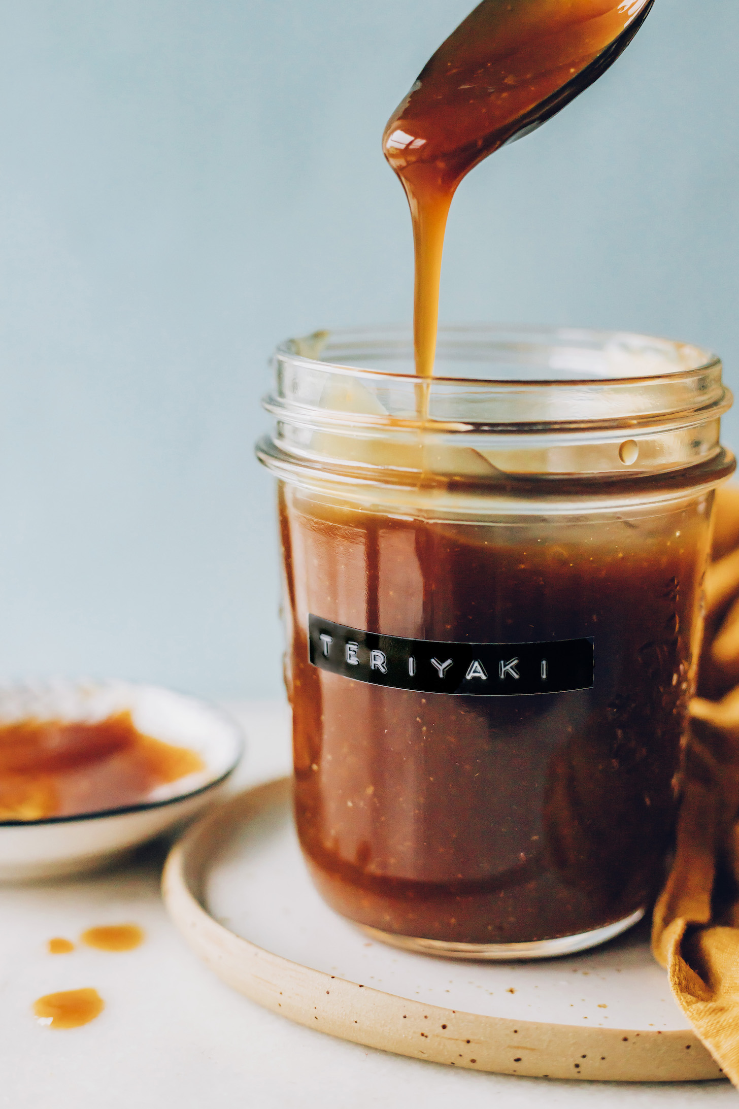 Teriyaki sauce dripping from a spoon into a jar