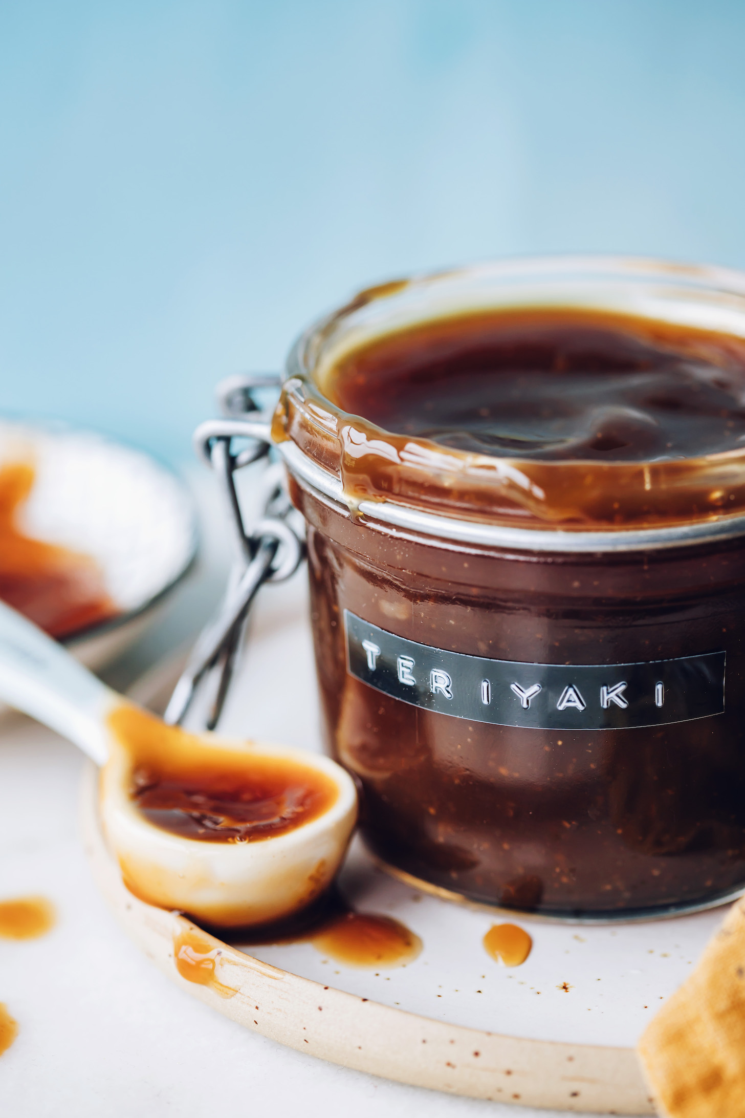 Spoonful of teriyaki sauce next to a jar of more sauce
