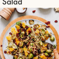 Hands holding a bowl of roasted fennel brussels sprout salad