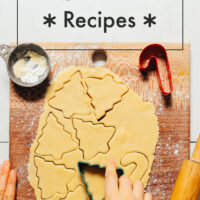 Hands cutting christmas trees out of rolled out sugar cookie dough