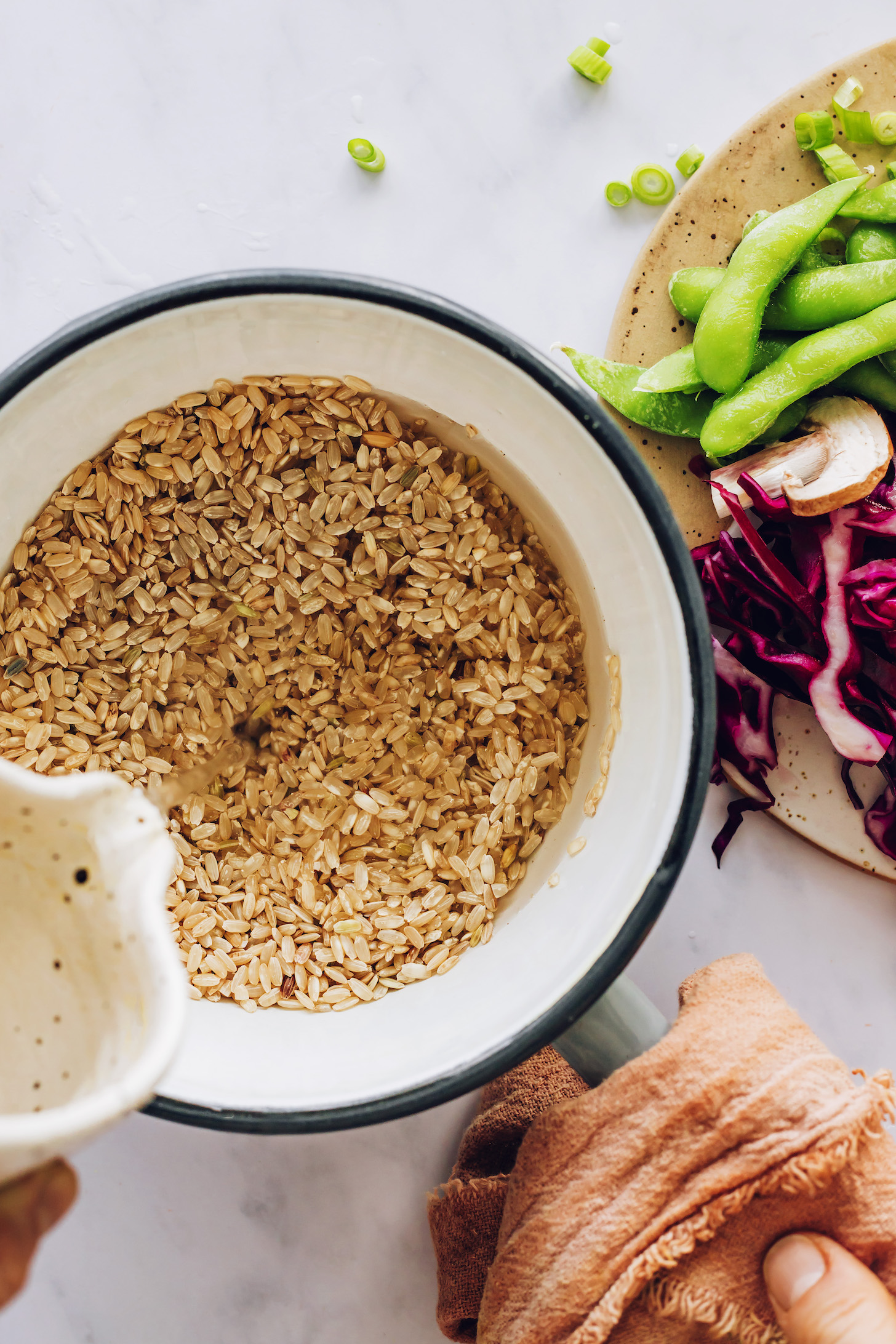 Pouring water over brown rice in a saucepan