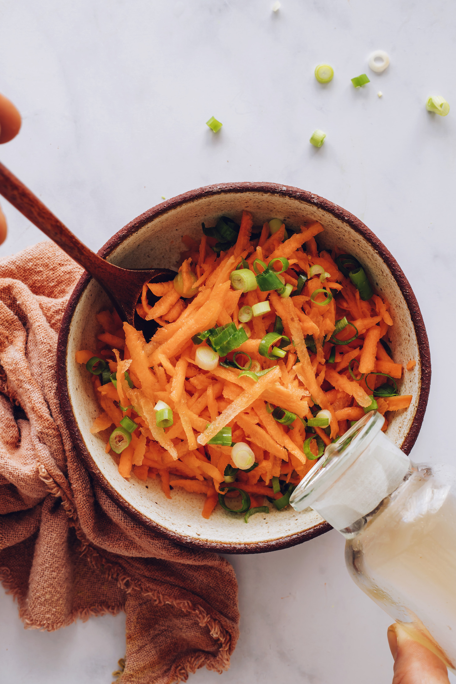 Adding rice vinegar to grated carrots and green onion