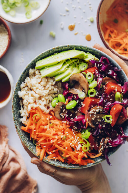 Holding a rainbow vegetable edamame bowl