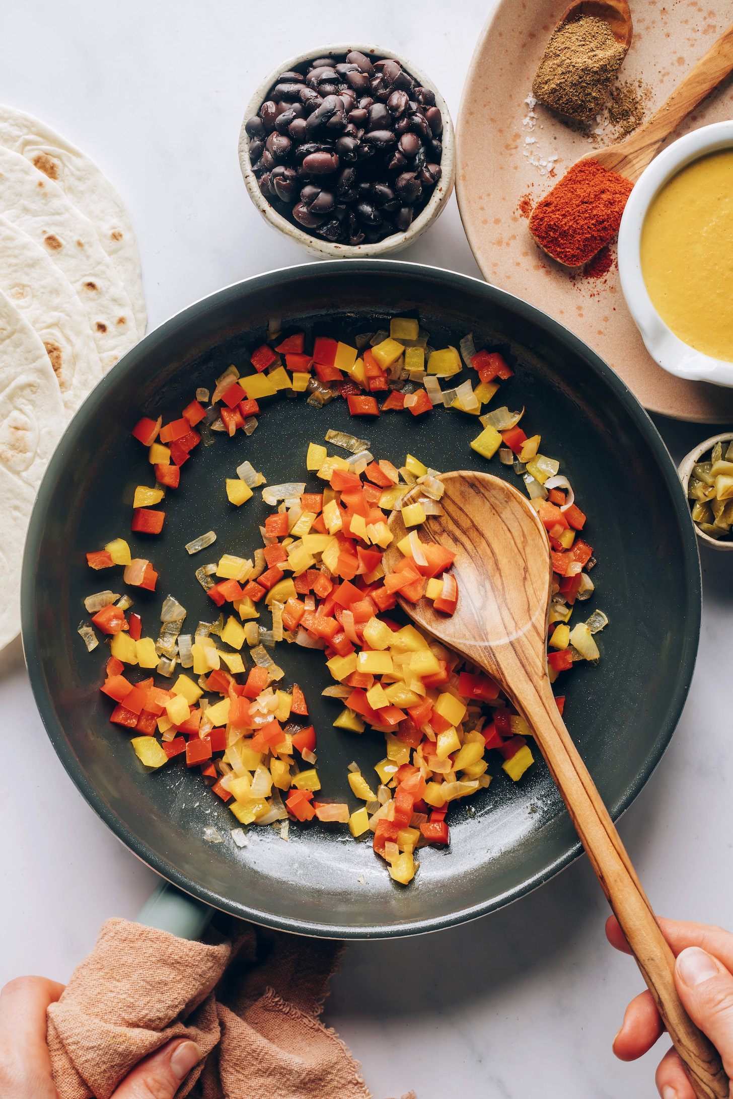 Sautéing onions and bell peppers in a skillet