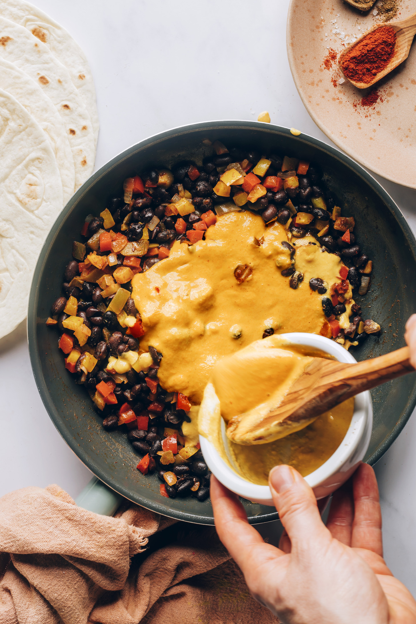 Adding dairy-free cheddar cheese to sautéed veggies and black beans