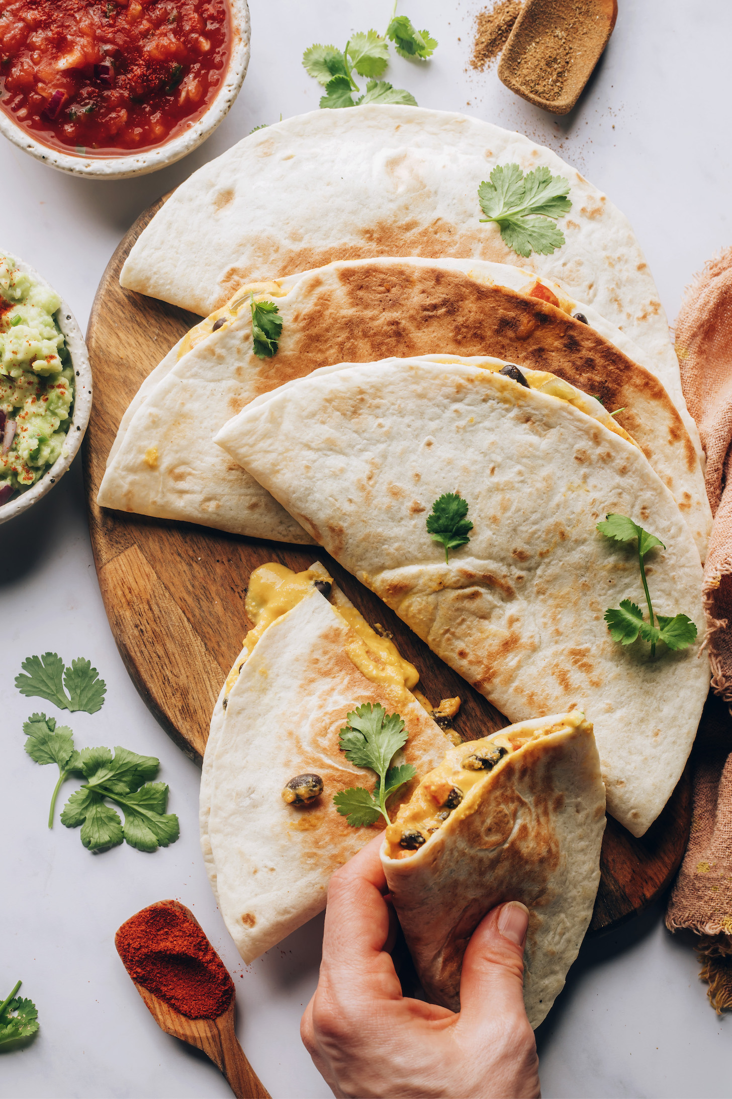 Holding a vegan quesadilla next to more quesadillas on a wood board