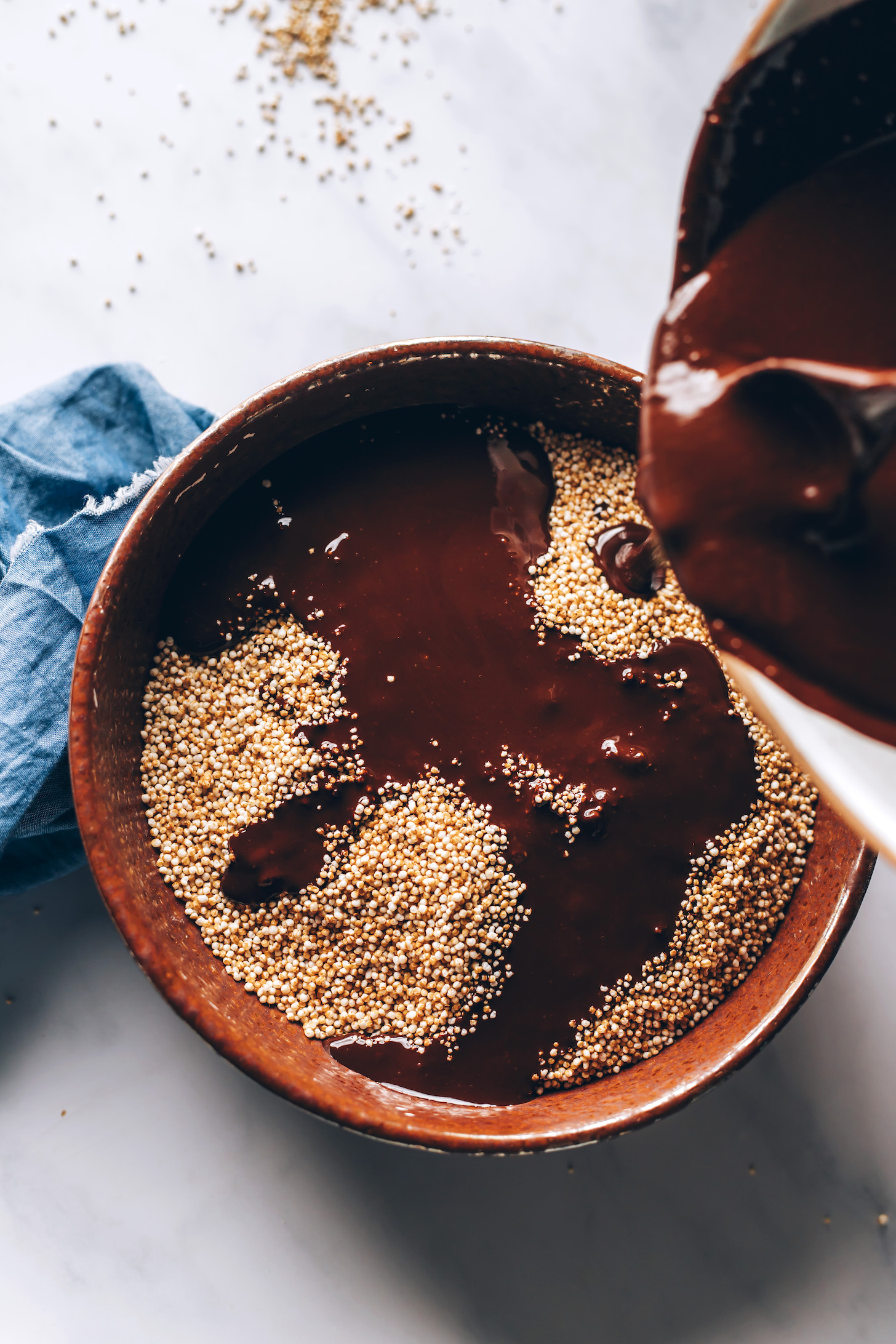 Pouring the melted chocolate mixture over puffed amaranth