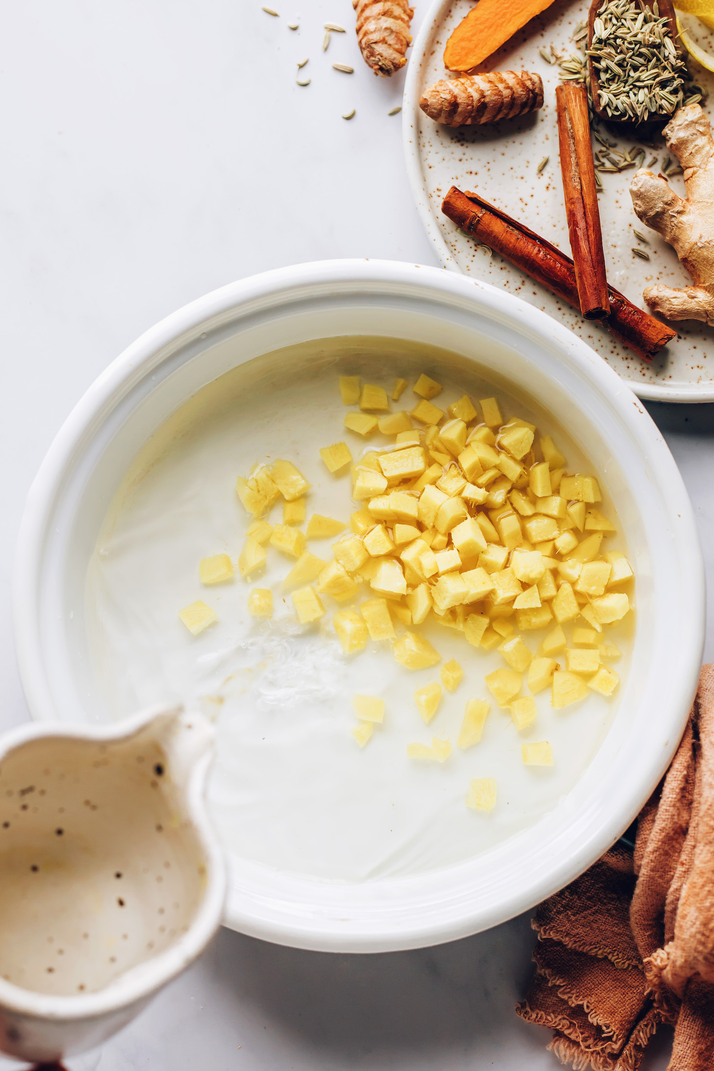 Pouring water over chopped ginger in a saucepan
