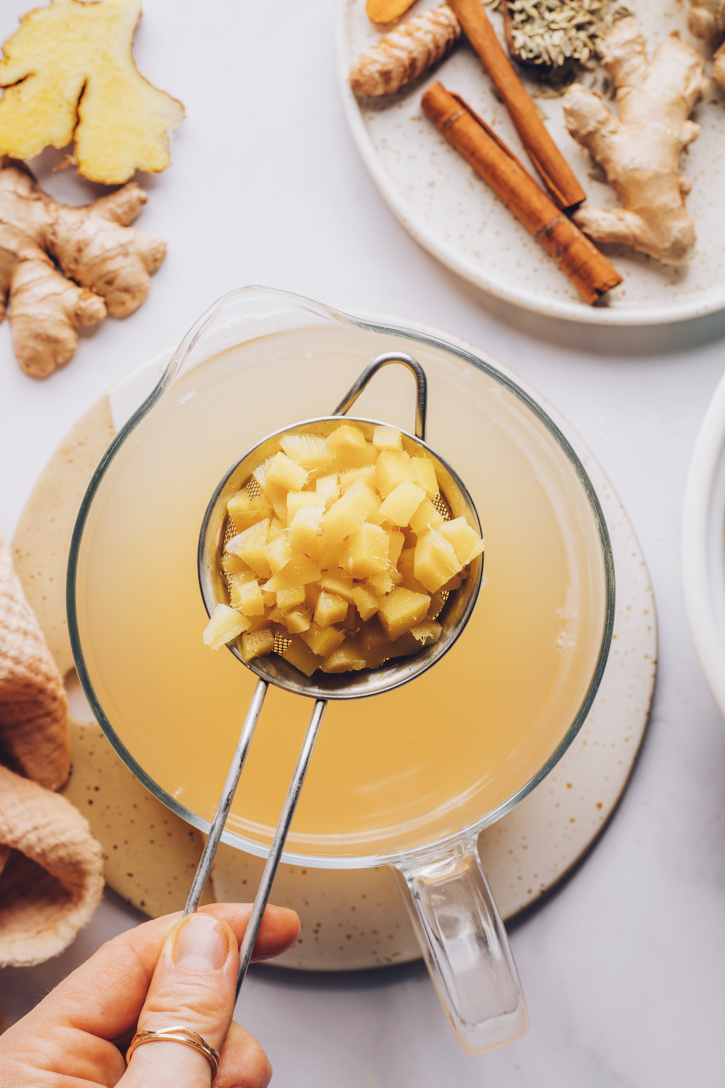 Chopped ginger in a strainer with ginger tea beneath it