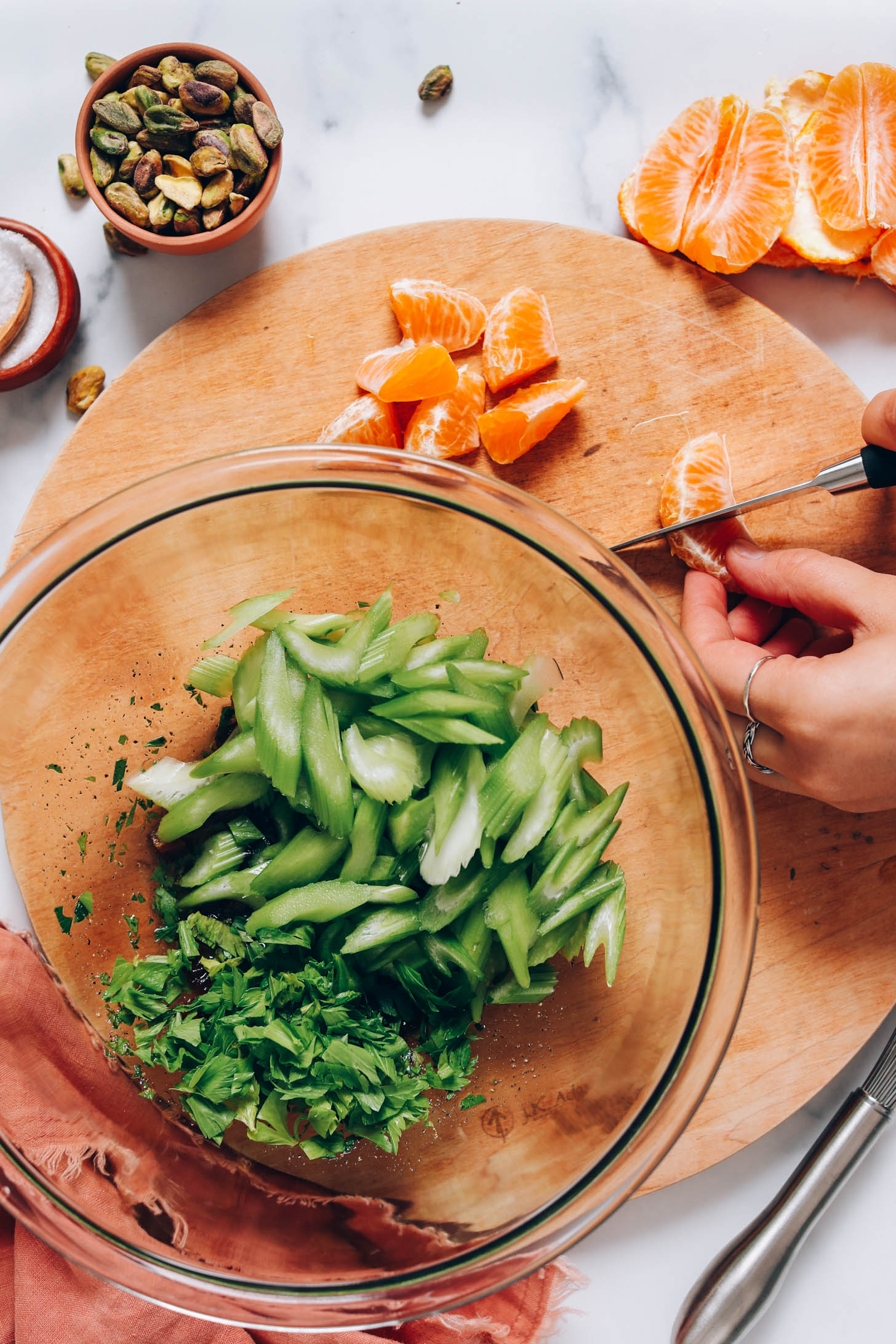 Slicing mandarins next to a bowl of celery and parsley