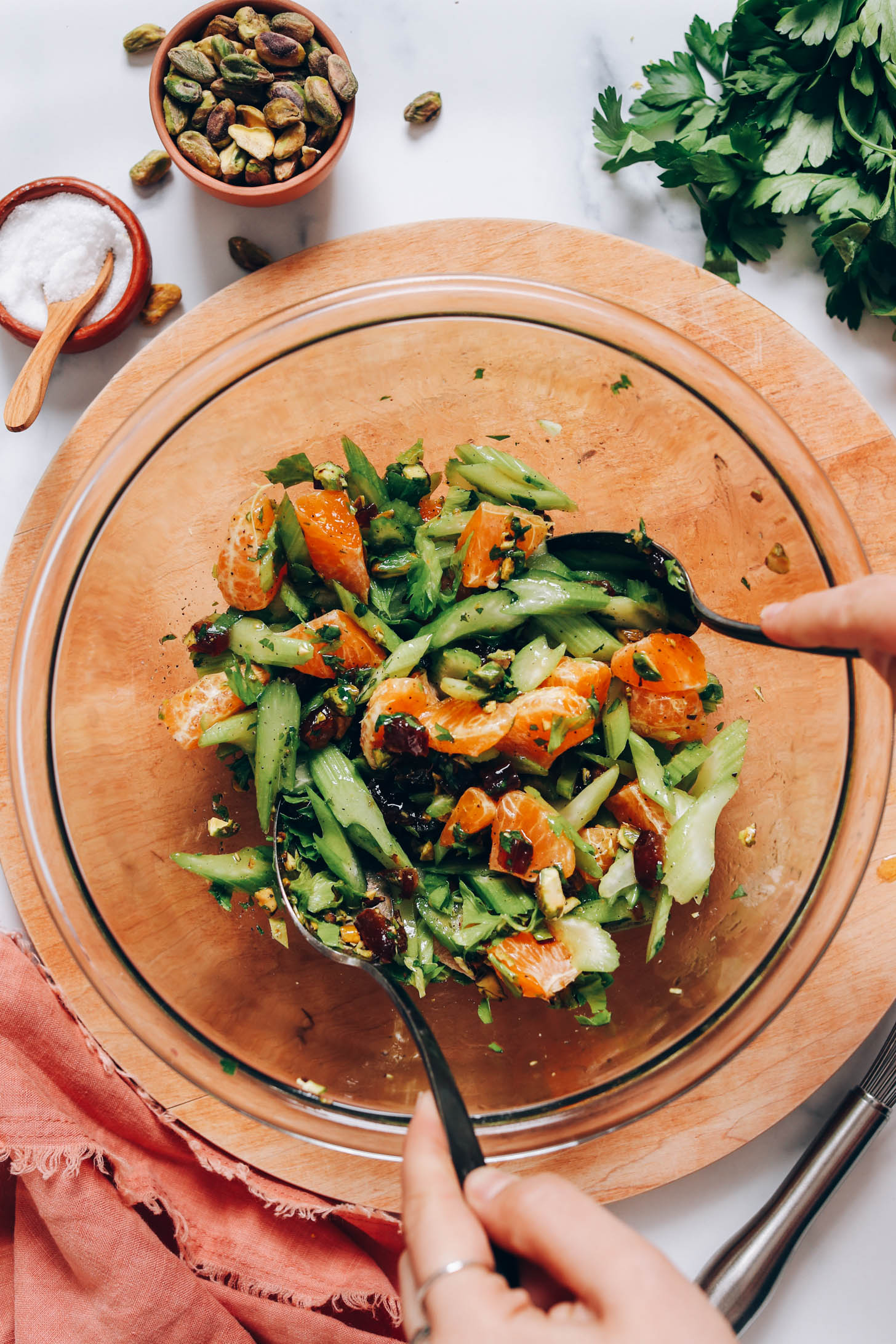 Using two spoons to mix celery salad with lemon olive oil dressing