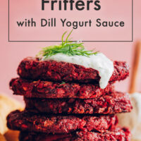 Stack of vegan and gluten-free beet fritters with dill yogurt sauce and fresh dill on top