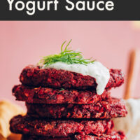 Stack of vegan and gluten-free beet fritters with dill yogurt sauce and fresh dill on top
