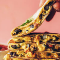 Picking up a vegan black bean quesadilla from a stack