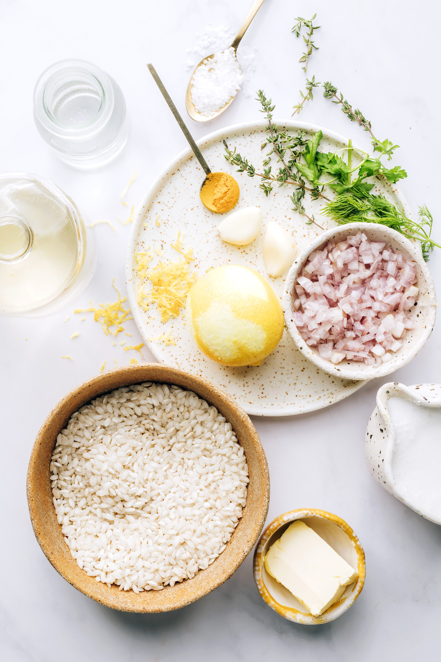 An ingredient shot of arborio rice, coconut milk, shallot, lemon, garlic, thyme, dill, parsley, white wine, and turmeric