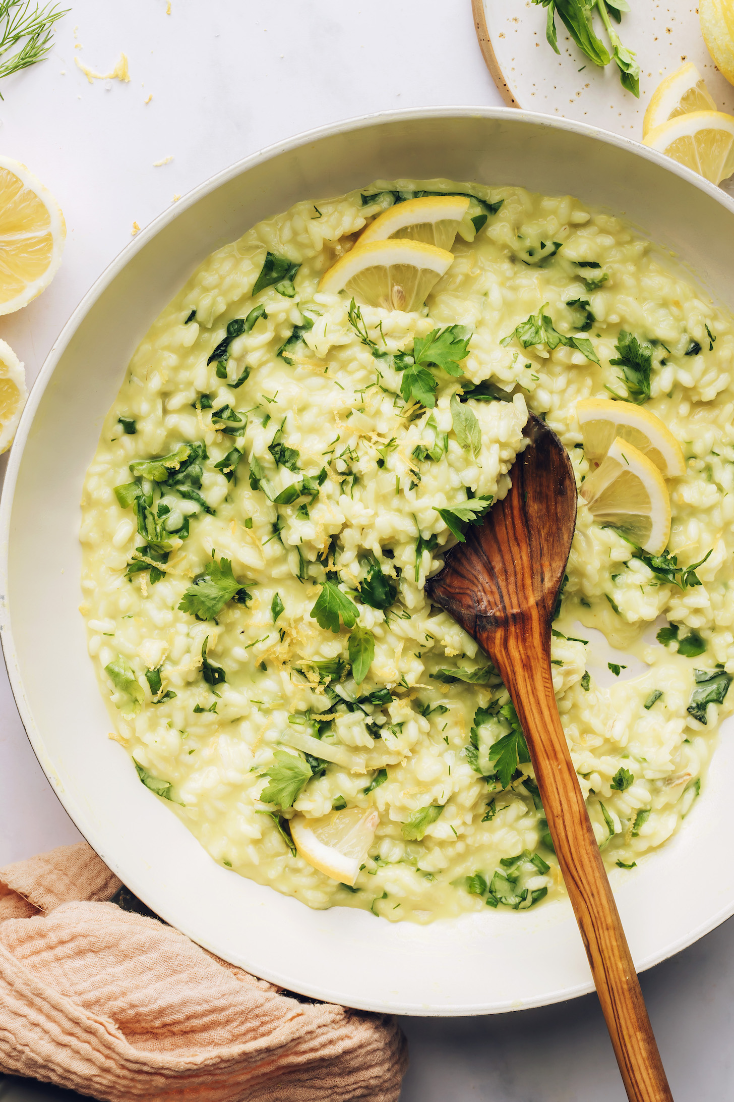 A wooden serving spoon in a large skillet of lemon risotto