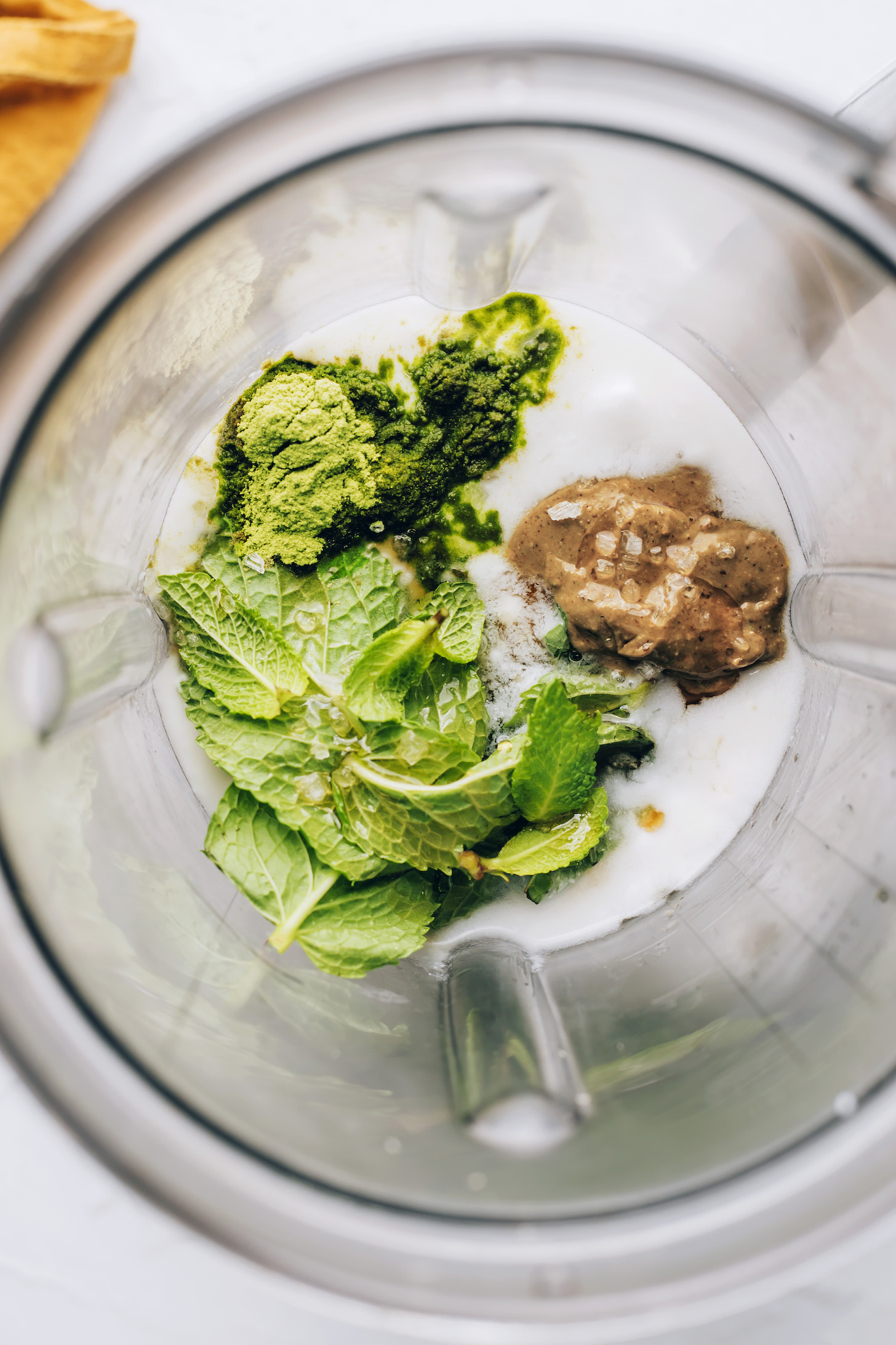 Coconut milk, fresh mint, matcha powder, and cashew butter in a blender