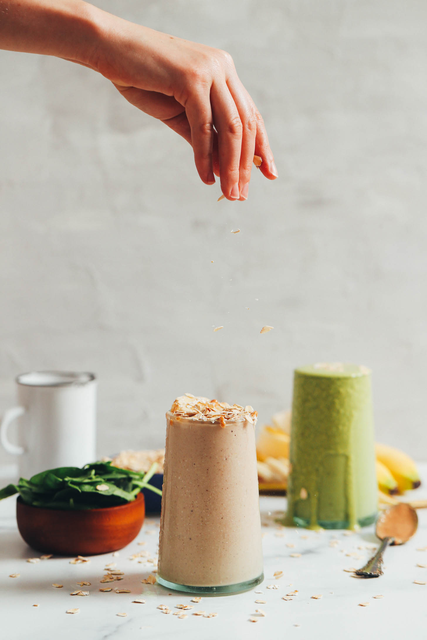Sprinkling oats over a peanut butter banana smoothie