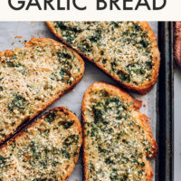 Slices of vegan garlic bread on a baking sheet