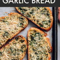 Slices of vegan garlic bread on a baking sheet