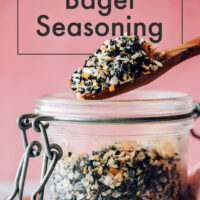 Spoon pouring a scoop of everything bagel seasoning into a jar