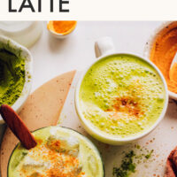 Mugs of vegan golden matcha lattes with turmeric sprinkled on top