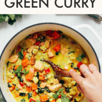 Hand stirring a pot of easy 1-pot salmon green curry