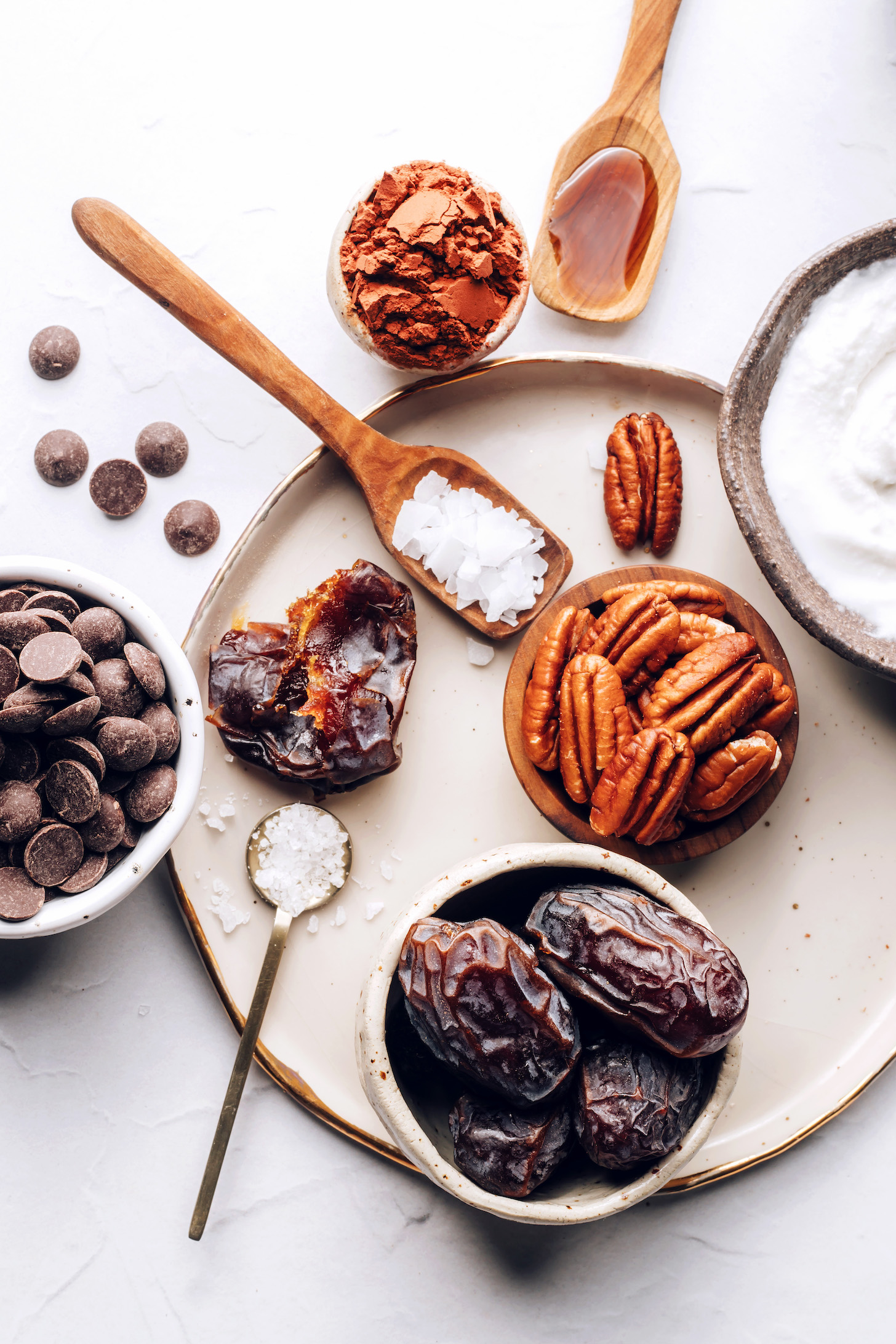 Ingredient shot with chocolate chips, dates, salt, pecans, coconut cream, vanilla, and cocoa powder