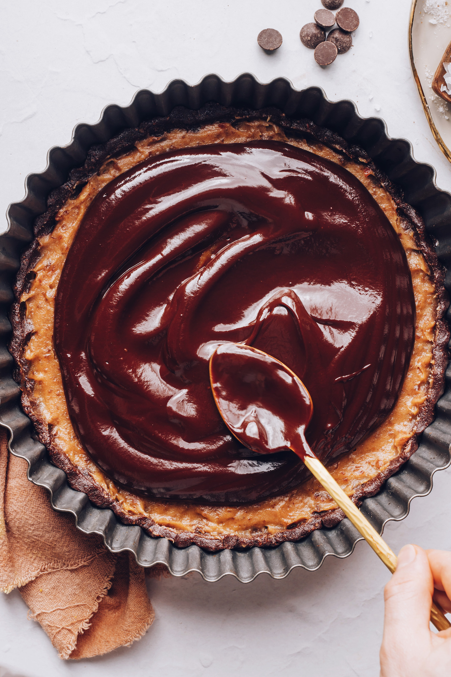 Spreading chocolate ganache over salted caramel