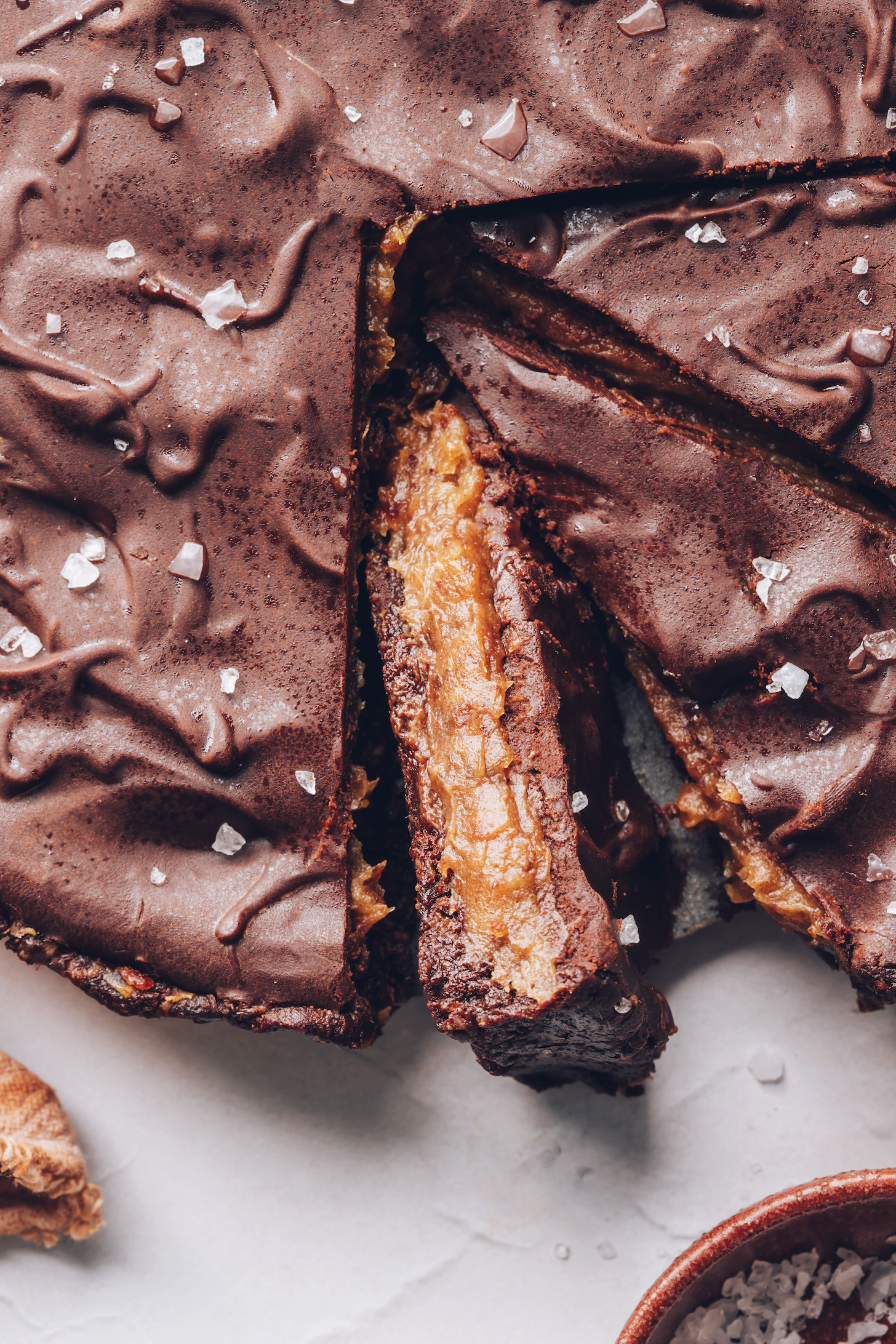 Partially sliced chocolate ganache tart sprinkled with flaky salt