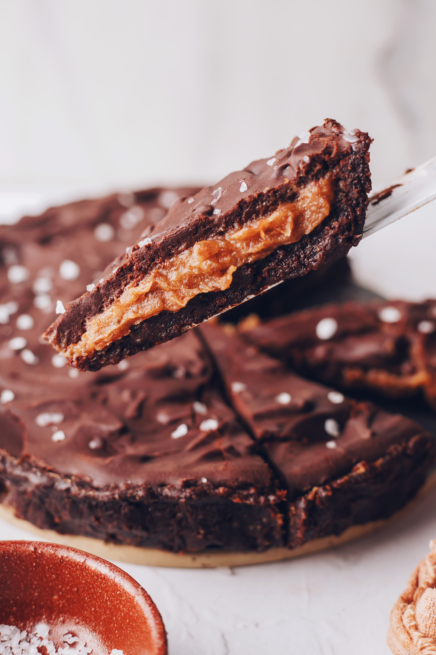 Holding up a slice of salted caramel chocolate ganache tart