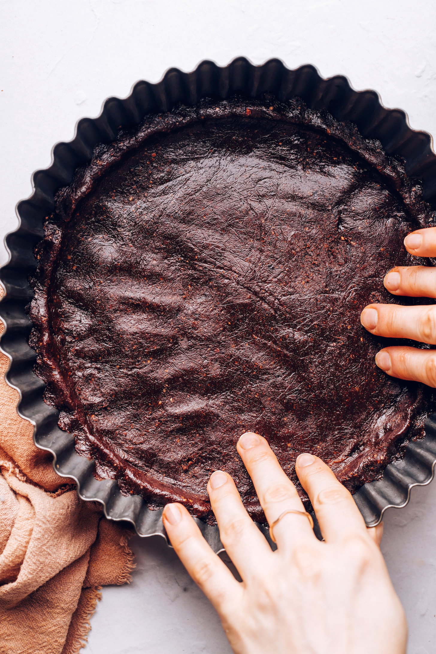 Pressing a chocolate pecan crust into a tart pan