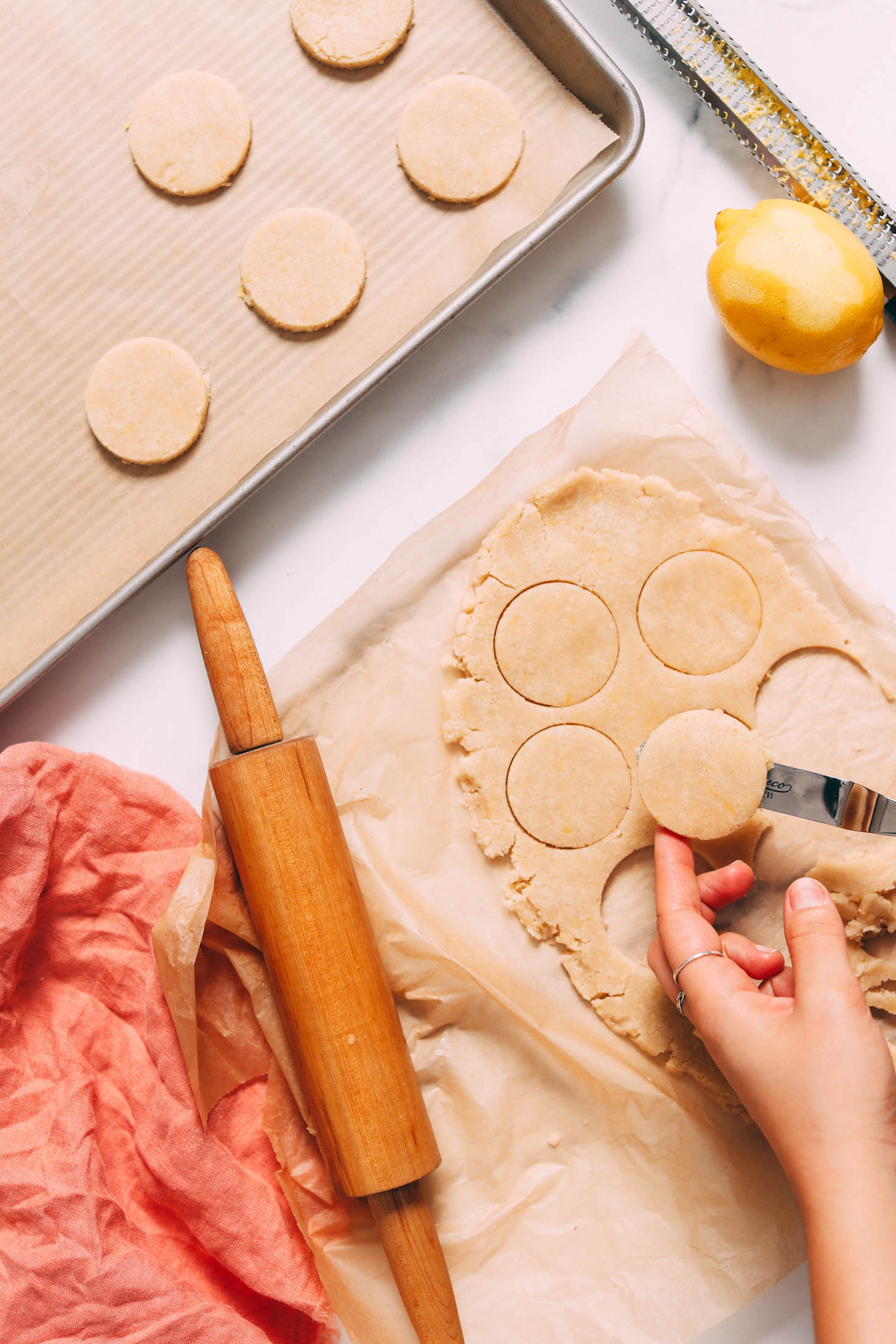 Using a spatula to transfer cut-out cookies to a baking sheet