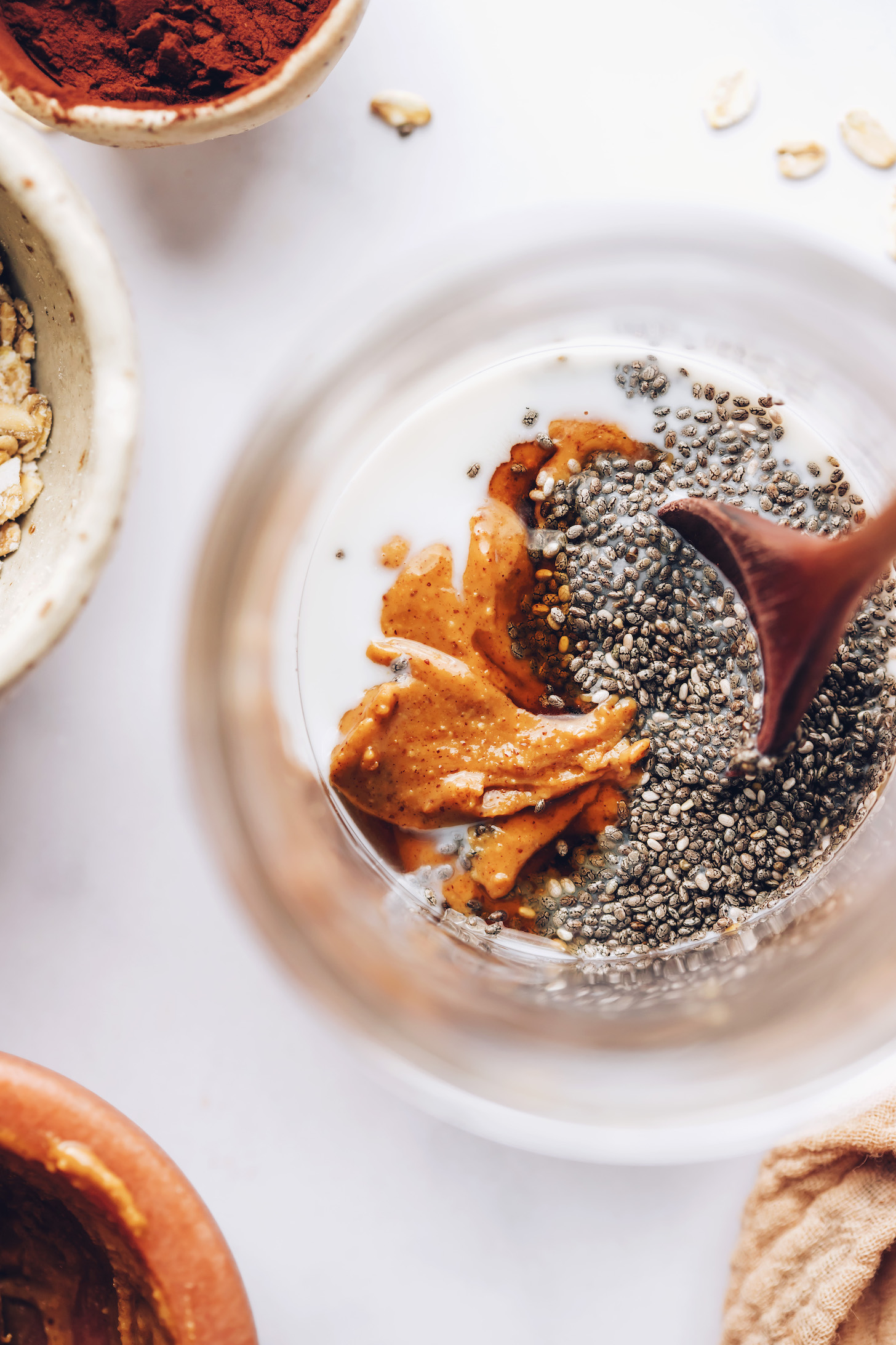 Stirring chia seeds, nut butter, maple syrup, and almond milk in a jar
