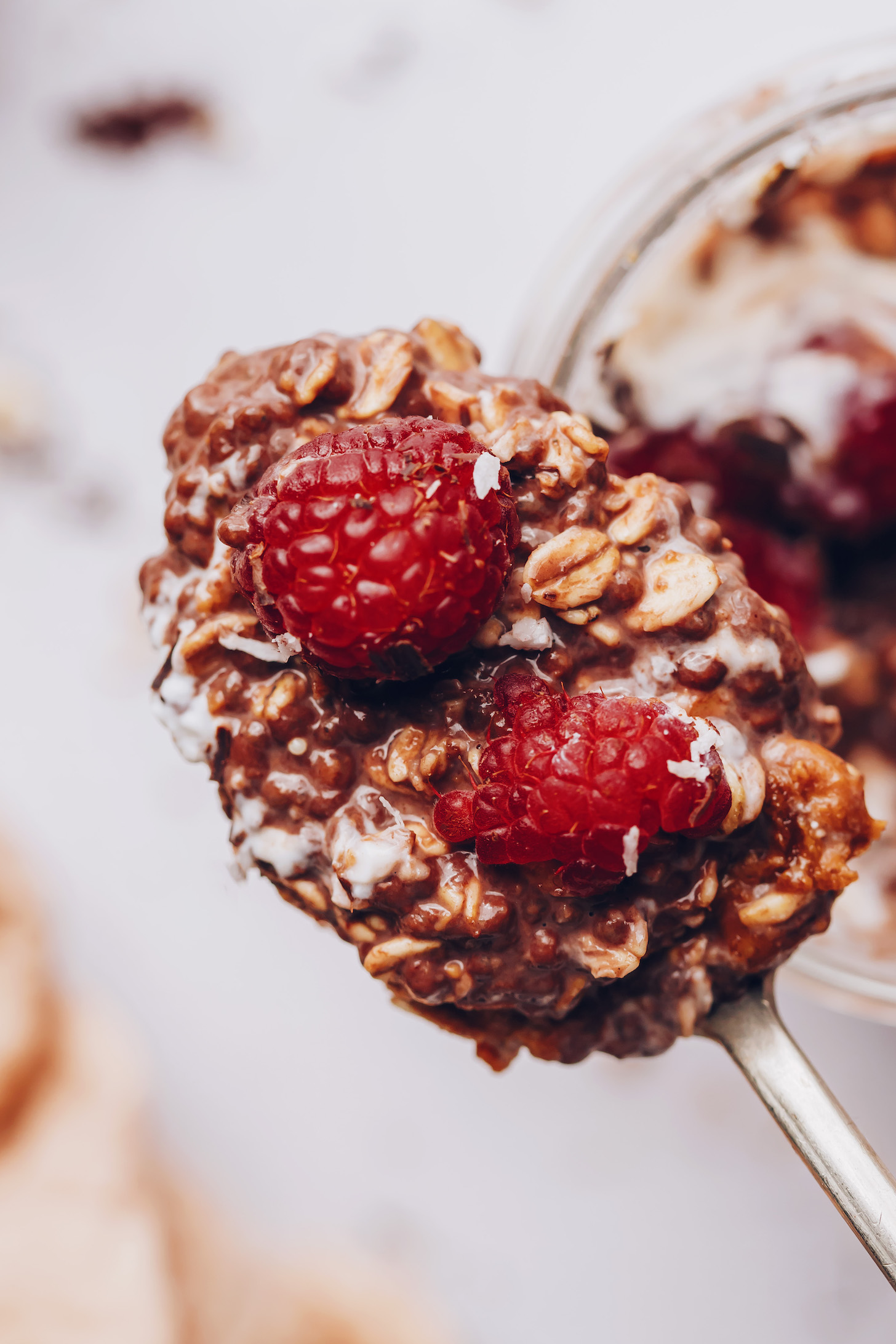 Close up photo of a spoonful of chocolate overnight oats with fresh raspberries