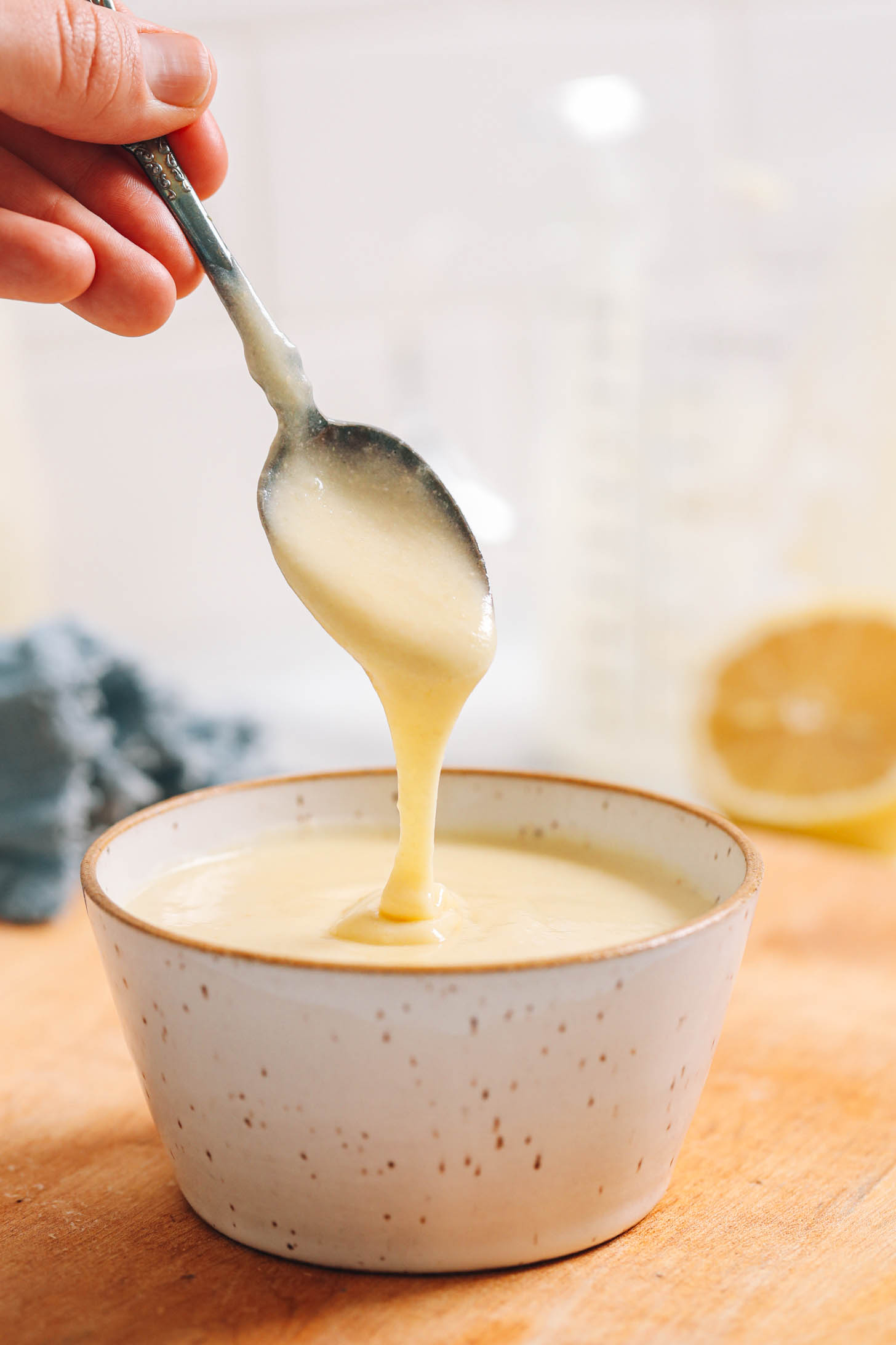 Vegan hollandaise sauce dripping from a spoon into a bowl