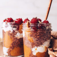 Two jars of chocolate overnight oats topped with fresh raspberries