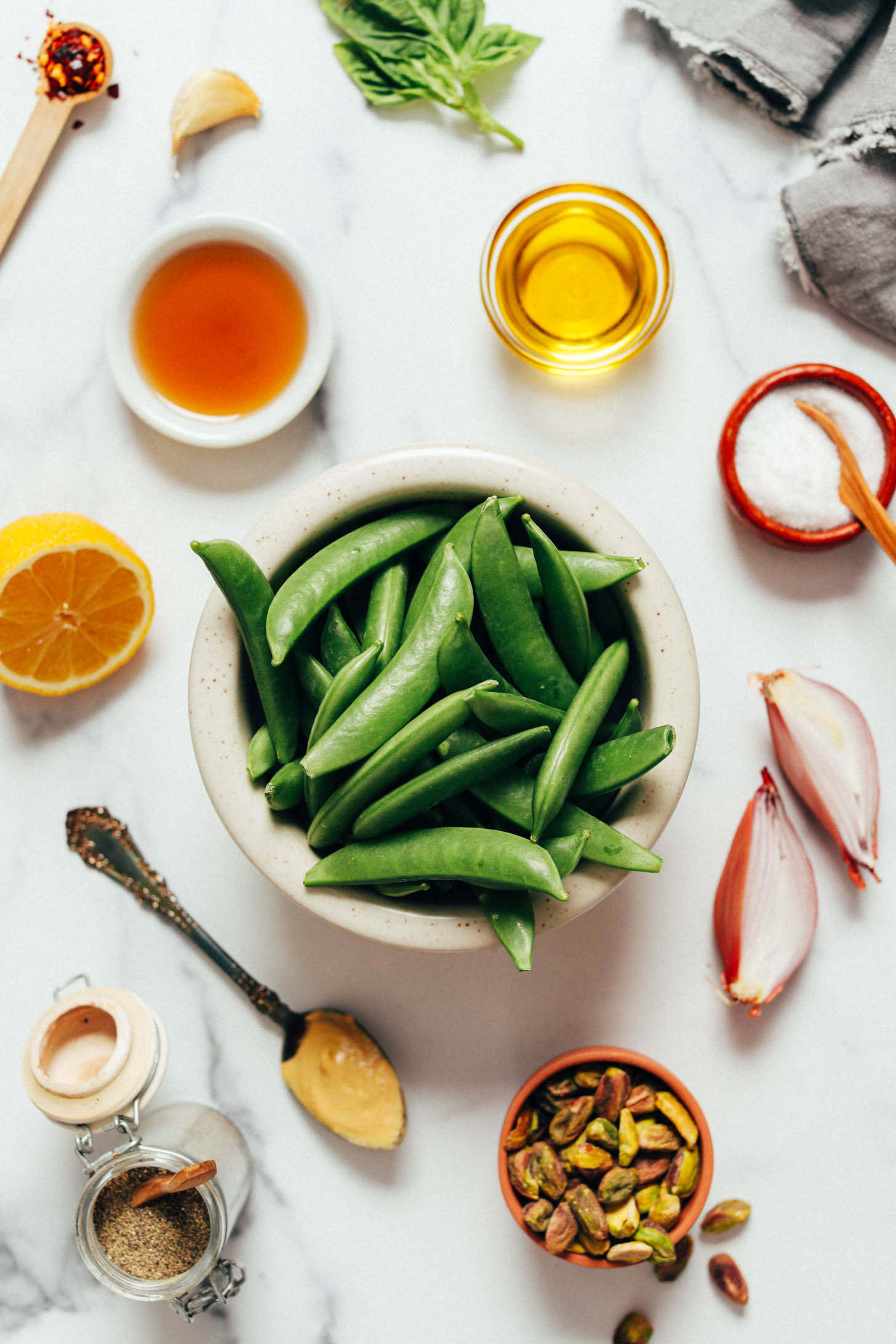 Red pepper flakes, garlic, basil, olive oil, salt, shallot, pistachios, mustard, black pepper, sugar snap peas, lemon, and maple syrup