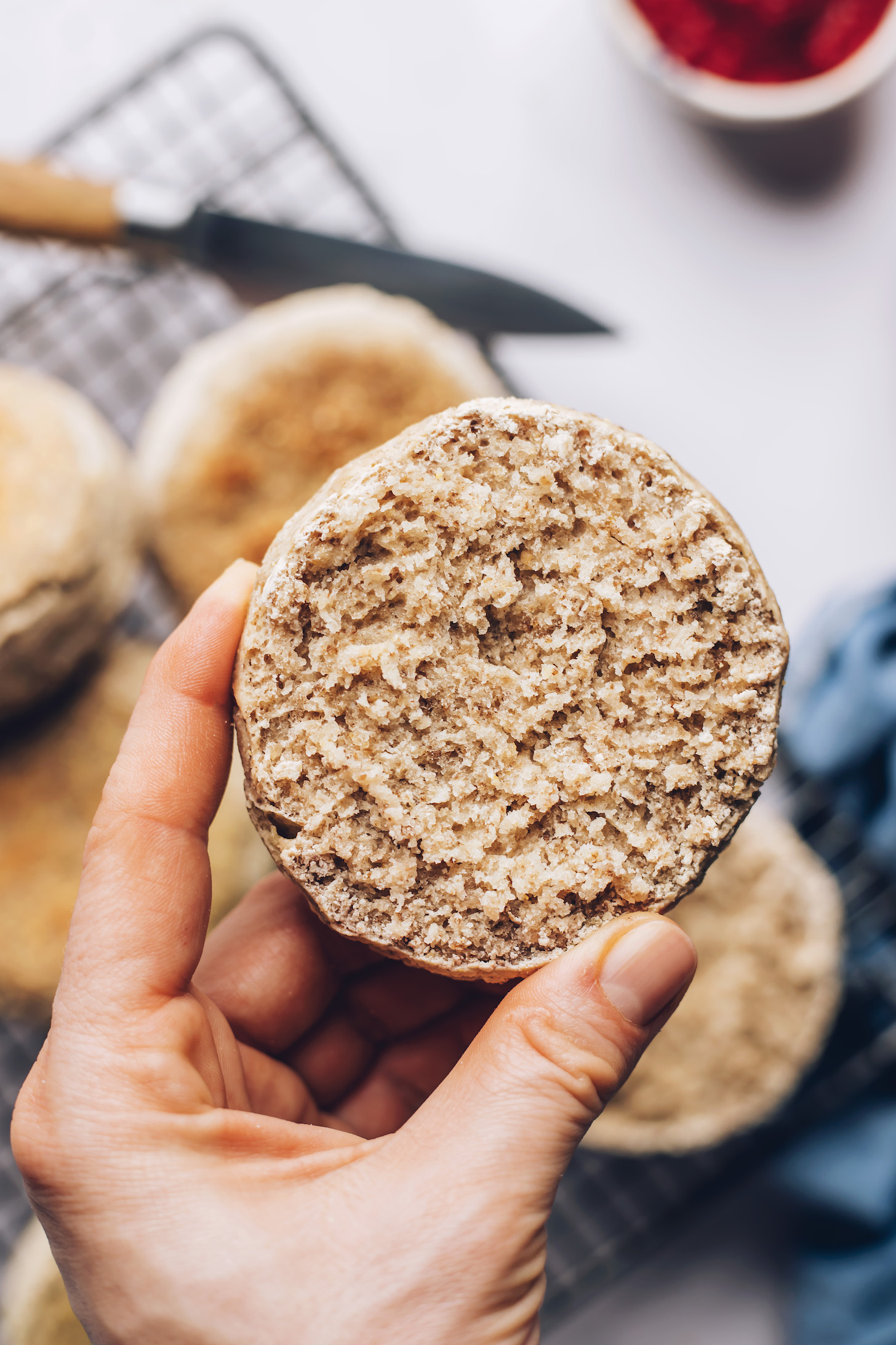 Hand holding up a sliced gluten-free English muffin to show the inner texture