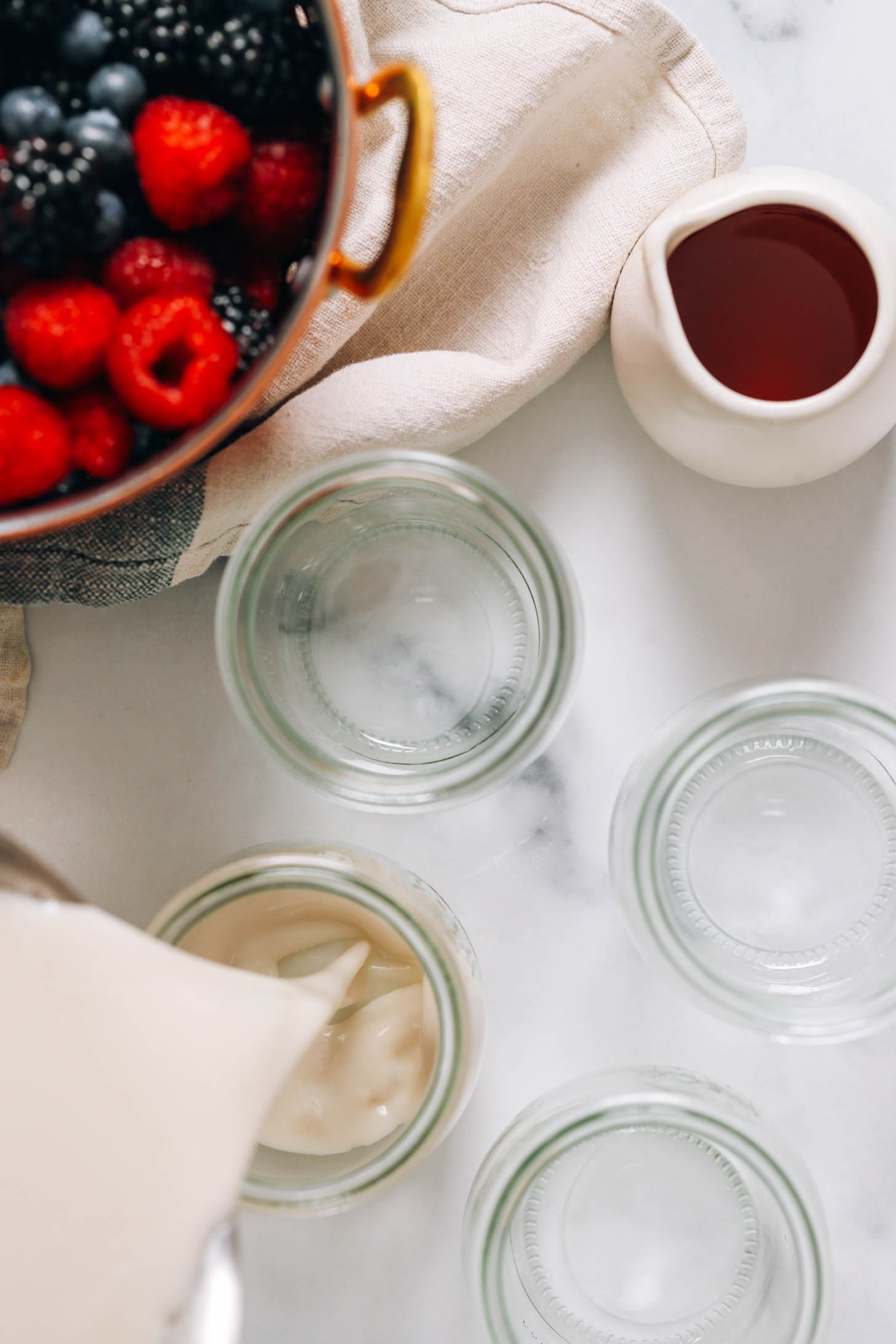 Pouring a warm coconut milk mixture into jars