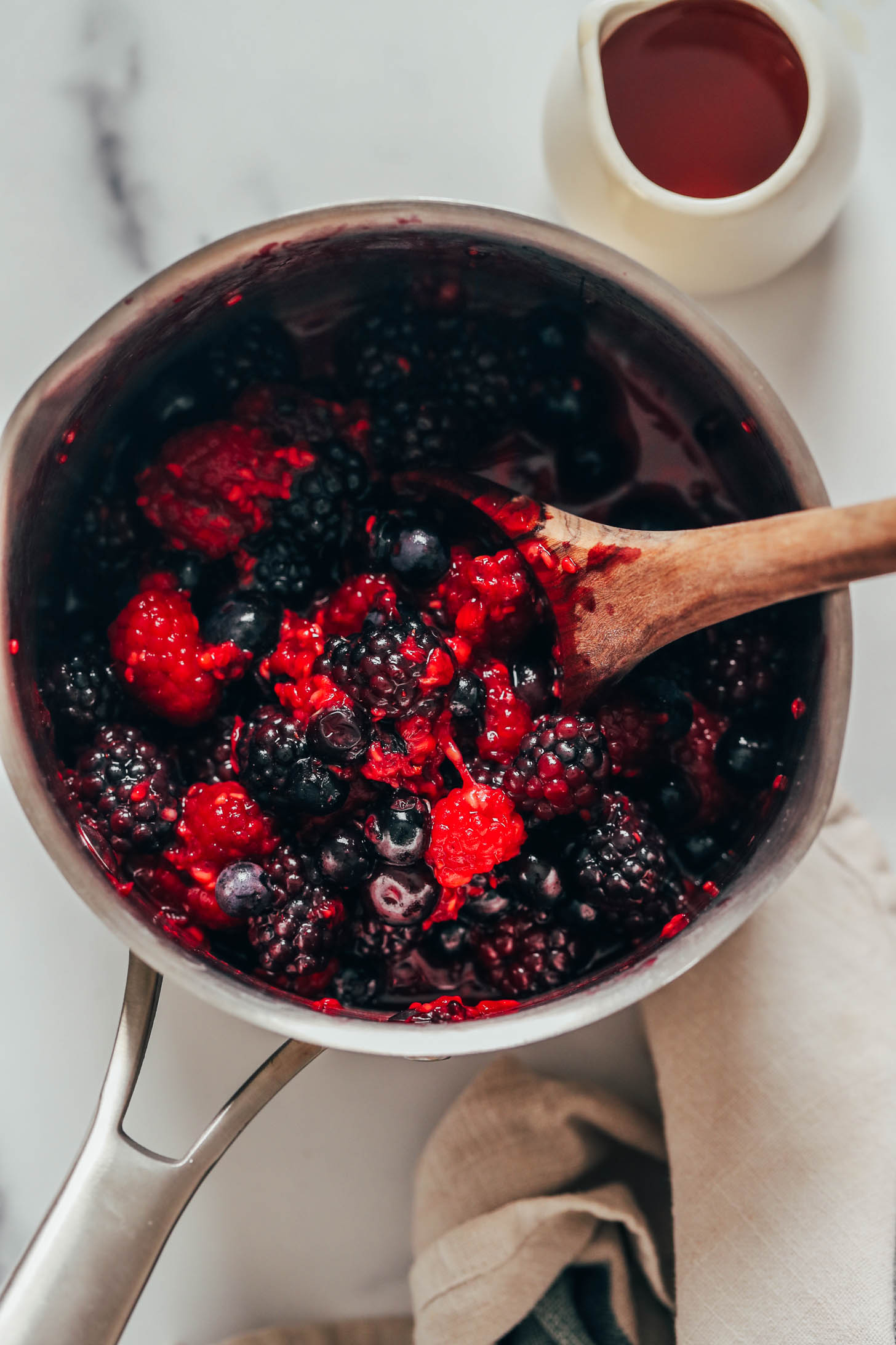 Wooden spoon in a saucepan of mixed berries