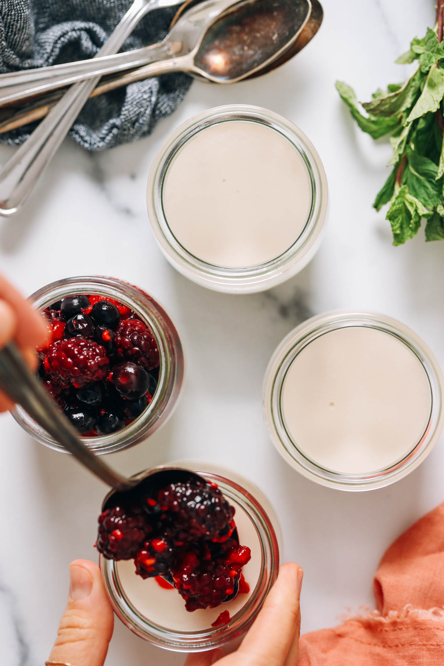 Adding warmed mixed berries over panna cotta
