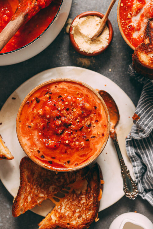 Vegan grilled cheese sandwich next to a bowl of tomato white bean soup