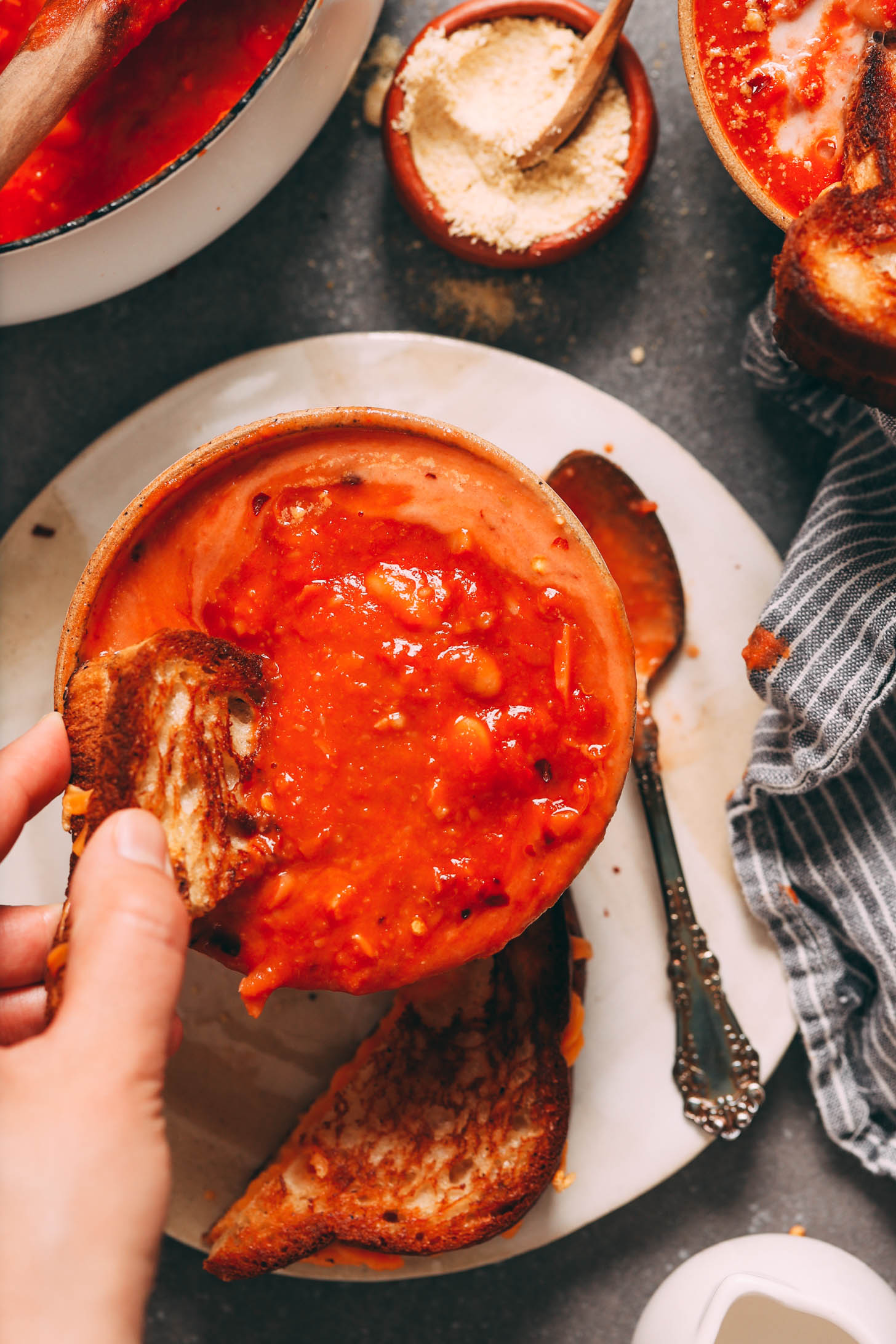 Dipping a grilled cheese sandwich into a bowl of tomato and white bean soup